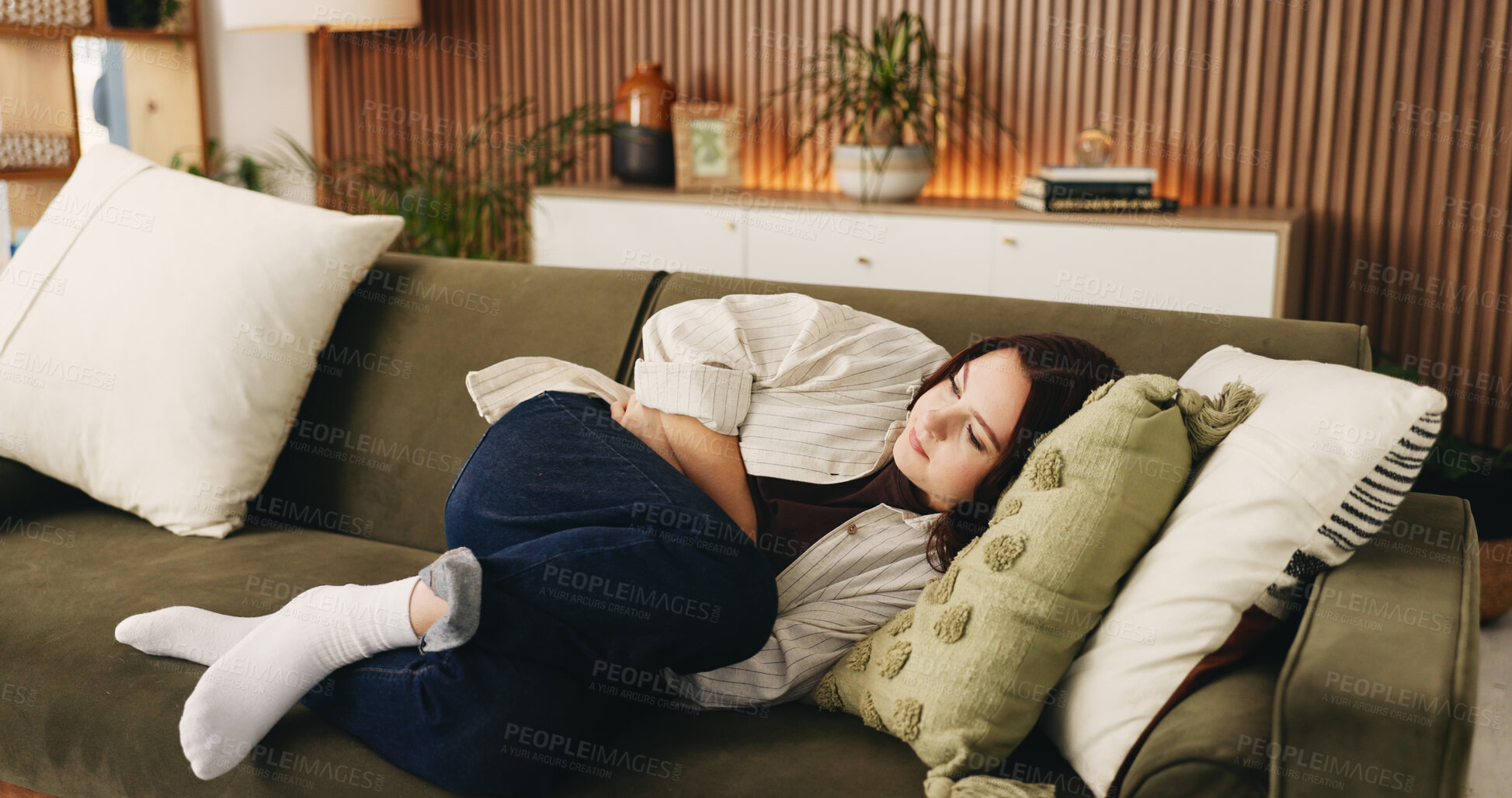 Buy stock photo Rest, menstruation and woman on couch with ibs, discomfort and stomach ache with symptoms. Health, fatigue and female person in house with cramps, endometriosis and abdominal pain for period.