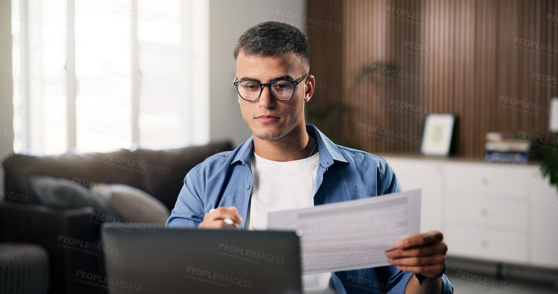 Buy stock photo Documents, laptop and remote work with man in home office for planning, research or review. Computer, paperwork and reading with freelance employee at desk in apartment for small business startup