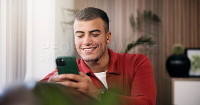 Buy stock photo Man, smartphone and relax with smile on sofa in home with contact, scroll or online dating in lounge. Person, happy and phone on couch for web chat, notification and post with social network at house