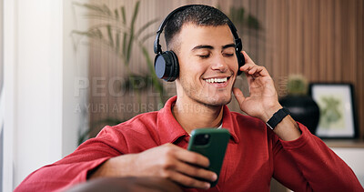 Buy stock photo Happy man, headphones and phone on sofa in home for audio, streaming service and relax in living room. Person, smartphone and listen to music with smile, subscription and scroll for song at apartment