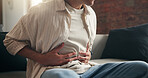 Man, hands and sick in home with stomach ache, indigestion and inflammation from diarrhea problem. Person, abdomen pain and medical issue on couch with constipation, bowel discomfort and bloating.