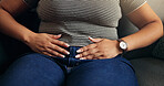 Hands, stomach ache and woman on sofa with pain, endometriosis or menstrual cramps in home. Living room, sore abdomen and sick person with constipation, food poisoning and bloated with gas in house