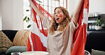 Woman, Denmark flag and celebration in home, soccer and cheering for game, shouting and winning. Fan, screaming and person in lounge, football and excited for score lead, expression or supporter