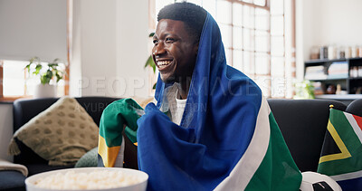 Buy stock photo Man, watching tv and South Africa flag for soccer on couch with goals, excited and support team in home. African person, smile and snack on sofa, streaming and global football competition in house