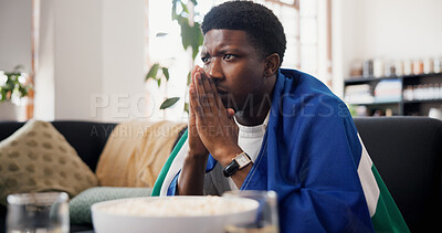 Buy stock photo Worried, man and watching tv in living room with sports match, concern and suspense for football game. Black person, stress and nervous in home with anxiety, flag and broadcast for soccer world cup.