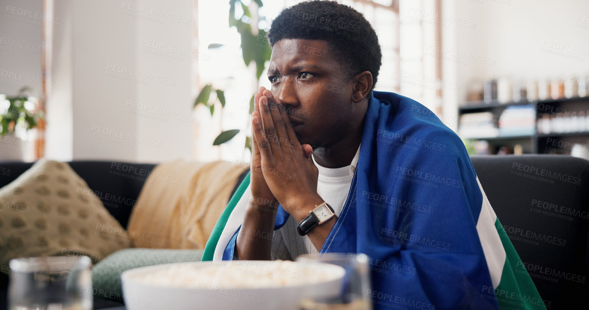 Buy stock photo Worried, man and watching tv in living room with sports match, concern and suspense for football game. Black person, stress and nervous in home with anxiety, flag and broadcast for soccer world cup.