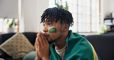 Buy stock photo Man, sports and watching tv on couch with Brazil flag, concern and suspense for football competition. Black person, stress or nervous in home with anxiety, tension and broadcast for soccer world cup.