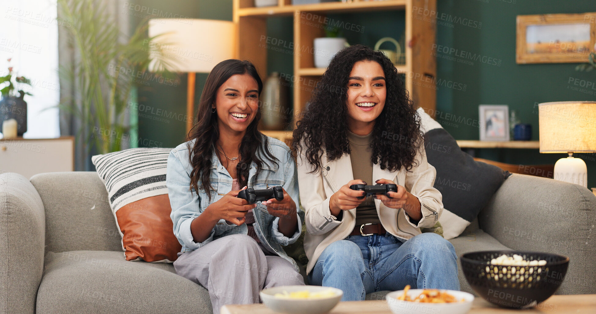 Buy stock photo Happy women, video games and playing with food on sofa for entertainment or online match in home. Female people, friends or smile with controller or snacks for console gaming or fun bonding in house