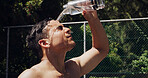 Basketball, break and water with man outdoor for recovery from competition, practice or training. Pouring, sports fatigue and tired with shirtless person on court for chilling, rest or refreshment