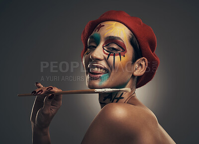 Buy stock photo Portrait, paintbrush and happy woman in studio with face paint, beret and passion for creative expression. Person, art tools and vibrant makeup with unique aesthetic, hat or smile on gray background.