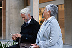 Mature business people talking in city senior businessman chatting to partner colleagues having conversation holding smartphones
