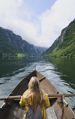 Buy stock photo Adventure, woman and river with rowing boat for travel, mountains and nature for holiday or vacation. Female person, journey and vessel on lake for sightseeing, back and wellness on trip in Norway 