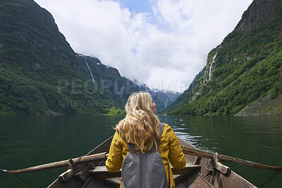 Buy stock photo Rowing, woman and river with boat for mountain adventure, travel and nature for holiday or vacation. Female person, journey and vessel on lake for sightseeing, back and wellness on trip in Norway 