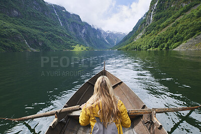 Buy stock photo Mountain, woman and river with rowing boat for travel, adventure and nature for holiday or vacation. Female person, journey and vessel on lake for sightseeing, back and wellness on trip in Norway 