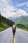 Adventure backpacking woman travels on road in epic majestic mountain snow landscape
