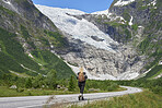Adventure backpacking woman travels on road in epic majestic mountain snow landscape