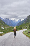 Adventure backpacking woman travels on road in epic majestic mountain snow landscape