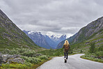 Adventure backpacking woman travels on road in epic majestic mountain snow landscape