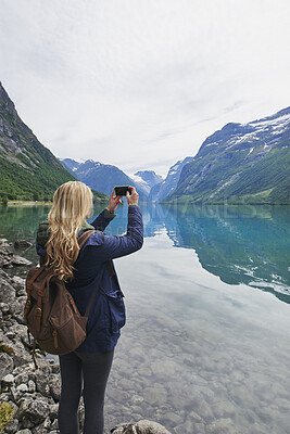 Buy stock photo Woman, mountain photography and travel outdoor by lake for adventure, holiday or hiking trip. Female person, river and taking picture for memory, space and sightseeing with backpack for trekking