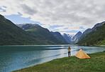 Adventure woman camping at beautiful lake in yellow tent view of majestic mountain inspiration escape