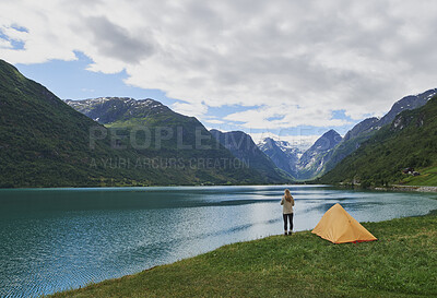 Buy stock photo Tent, nature and woman by lake outdoor in morning for adventure, holiday or vacation with travel. Mountain, explore and female person by canopy at river for weekend trip with calm, peace or relax.