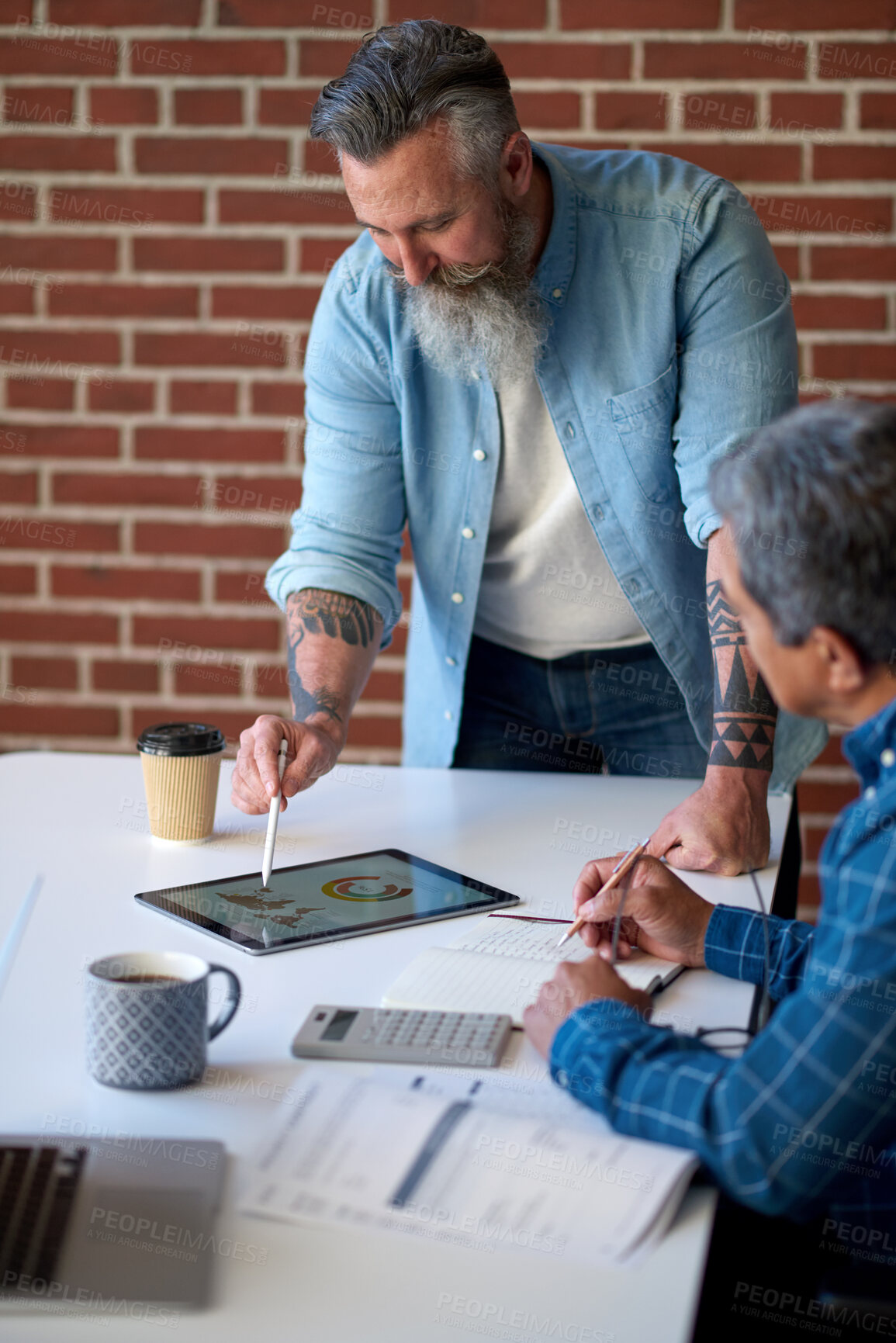 Buy stock photo two businessmen using tablet computer discussing financial graph data on mobile touchscreen device in meeting