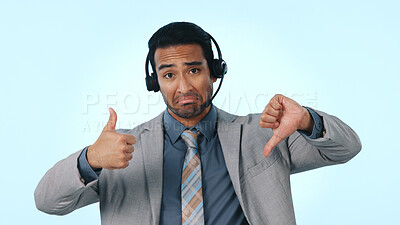 Buy stock photo Telemarketing, portrait and man with headset, thumb down and gesture for approval or negative review. Confused, blue background and person with mic in studio, recommend and feedback with sign