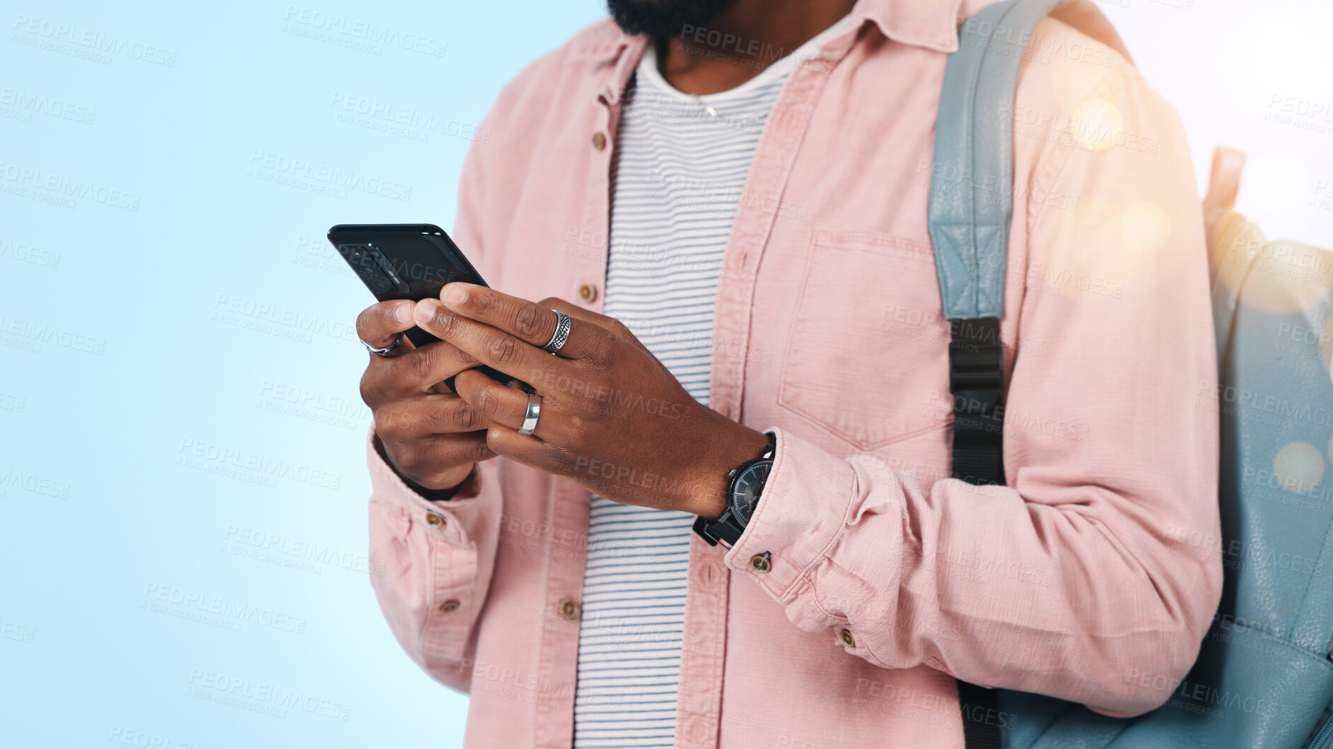 Buy stock photo Phone, hands and man in studio with backpack for notification, email or contact for college application. Tech, typing and student on mobile app for university results by blue background with bokeh