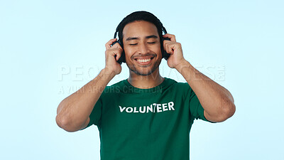 Buy stock photo Studio, volunteer and man with headphones, charity and listening to music with subscription on break. Blue background, humanitarian and happy person with tech for playlist, ngo and streaming audio
