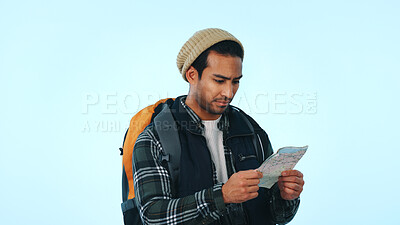 Buy stock photo Man, hiker and backpack with map in studio for location or lost direction on a blue background. Male person, traveler or checking coordinates with tour guide for navigation, route or trekking trip