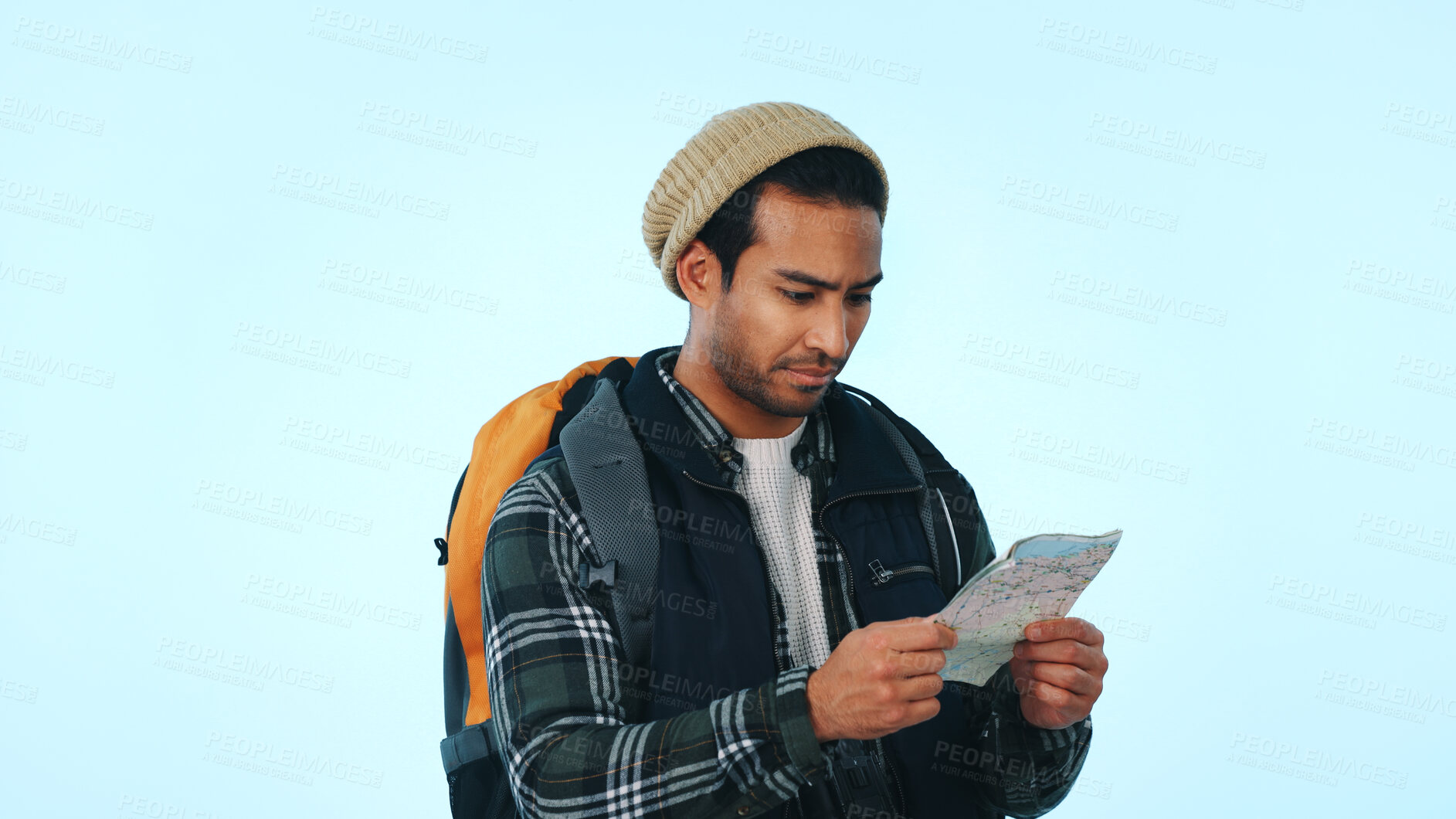 Buy stock photo Man, hiker and backpack with map in studio for location or lost direction on a blue background. Male person, traveler or checking coordinates with tour guide for navigation, route or trekking trip