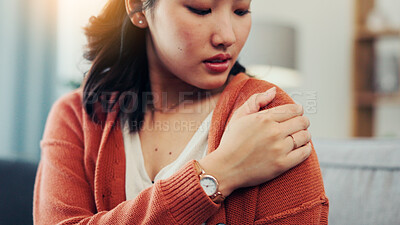 Buy stock photo Shoulder, pain and Asian woman on sofa with injury for fibromyalgia, osteoporosis and inflammation. Home, upset and person massage arm for strain, muscle tension and joint ache in living room