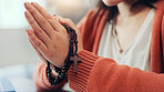 Praying, rosary and hands of woman in home for religion, worship and belief for gratitude. Christianity, religious and person in prayer for peace, blessing or guidance with spiritual jewelry in house