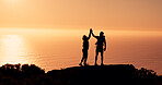 People, silhouette or hiking with high five on mountain cliff for achievement or accomplishment. Sunset, hikers or team with hands together in nature for trekking journey, success or conquer on space