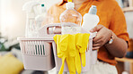 Cleaning, basket and hands of woman in home for chemicals, sanitary tools and bacteria prevention. Spray, housekeeping and disinfection product with person in apartment for equipment and supplies