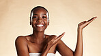 Portrait, black woman and pointing with skincare in studio background for beauty, promo and results. Smile, person and hand gesture for advertising, facial cosmetics and information for healthy skin
