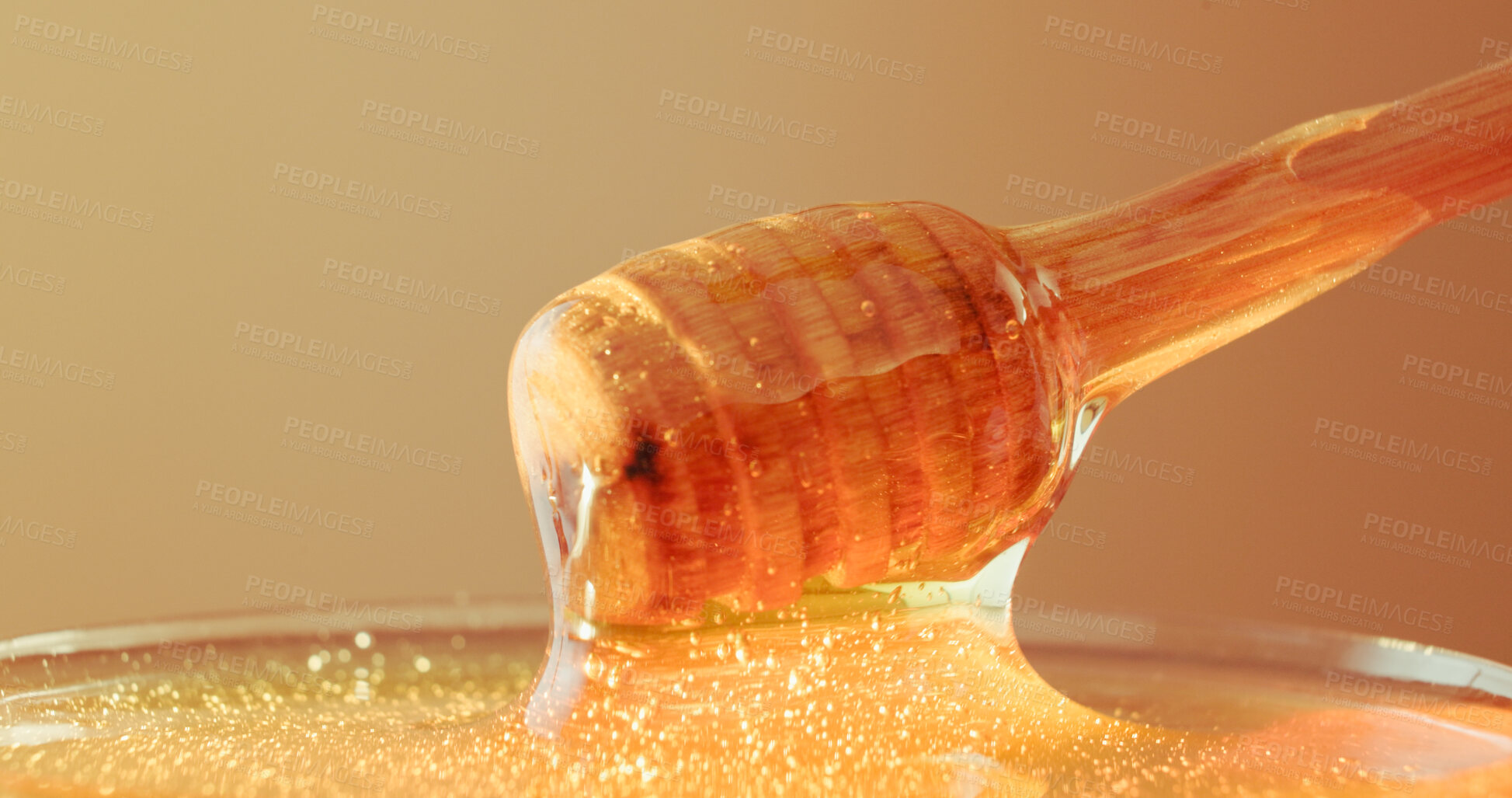 Buy stock photo Studio, bowl and honey on wooden dipper, natural antioxidant and organic ingredient for sweetener. Syrup, sticky liquid and utensil with raw sugar for immunity, healthy food and brown background