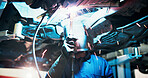 Mechanic, welding and person in workshop by car for diagnostics, maintenance or auto service. Garage, sparks and technician with equipment for vehicle inspection, fixing or engine repair with helmet