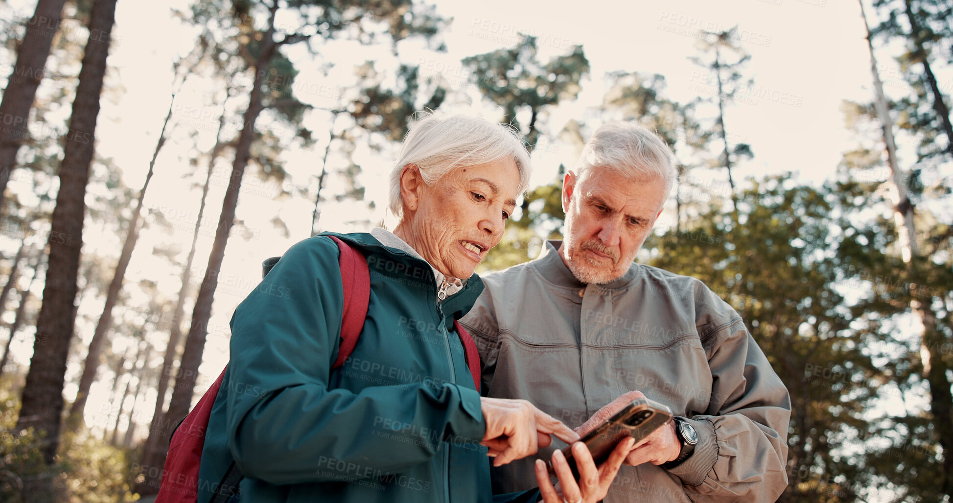Buy stock photo Hiking, old couple and travel with smartphone for direction, talk or search for location on website. Outdoor, backpacker and elderly people with mobile for digital map, low angle and lost together