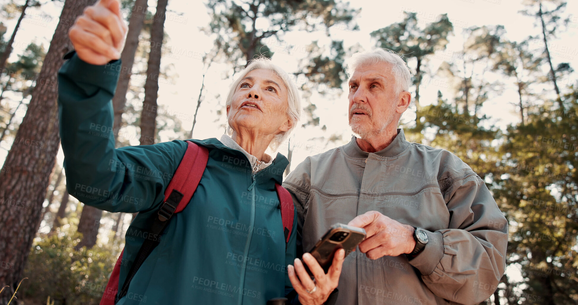 Buy stock photo Hiking, old couple and travel with smartphone in woods, talking or searching for location on website. Outdoor, backpacker and elderly people with digital map on holiday, low angle and lost together
