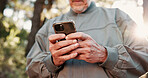 Hiking, phone and hands of senior man in forest for wellness, fresh air and online for direction. Travel, morning and elderly person on nature trail for adventure, health and exercise on smartphone