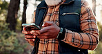Hiking, phone and hands of old man in nature for wellness, fresh air and online for direction. Travel, typing and elderly person on smartphone for mobile app, health and exercise on outdoor trail