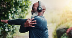 Stretching, runner and headphones with black man in nature for fitness playlist, streaming and health. Workout podcast, muscle warm up and training with senior person outdoor for wellness and radio