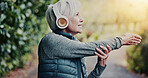 Outdoor, stretching and old woman with headphones at park, think and listening to music for workout. Wellness, audio and senior person with tech for fitness, retirement or happy for warm up in nature