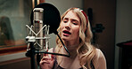 Artist, woman and singing in recording studio with microphone, song performance and music production. Creative, person and singer at record label with gear, talenr and sound track for album project.
