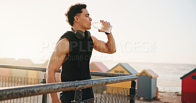 Buy stock photo Beach, fitness and man with water on break, reflection and drinking liquid after training in nature. Outdoor, space and person with bottle for wellness, exercise and cool down with mineral hydration