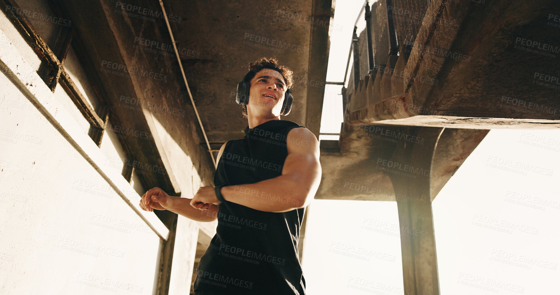 Buy stock photo Stretching, fitness and man in city with headphones for exercise, workout and ready for training. Low angle, outdoor and person with muscle warm up for mobility, health and active hobby with music