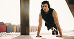 Athlete, pushups and man with headphones on beach, fitness or serious for health with music playlist. Outdoor, endurance and person with tech for audio, training and exercise routine for wellness