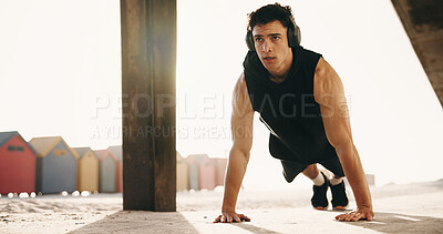Buy stock photo Athlete, pushups and man with headphones on beach, fitness or serious for health with music playlist. Outdoor, endurance and person with tech for audio, training and exercise routine for wellness