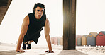 Fitness, pushups and man with headphones on beach, athlete or serious for health with music playlist. Outdoor, endurance and person with tech for audio, training and exercise routine for wellness